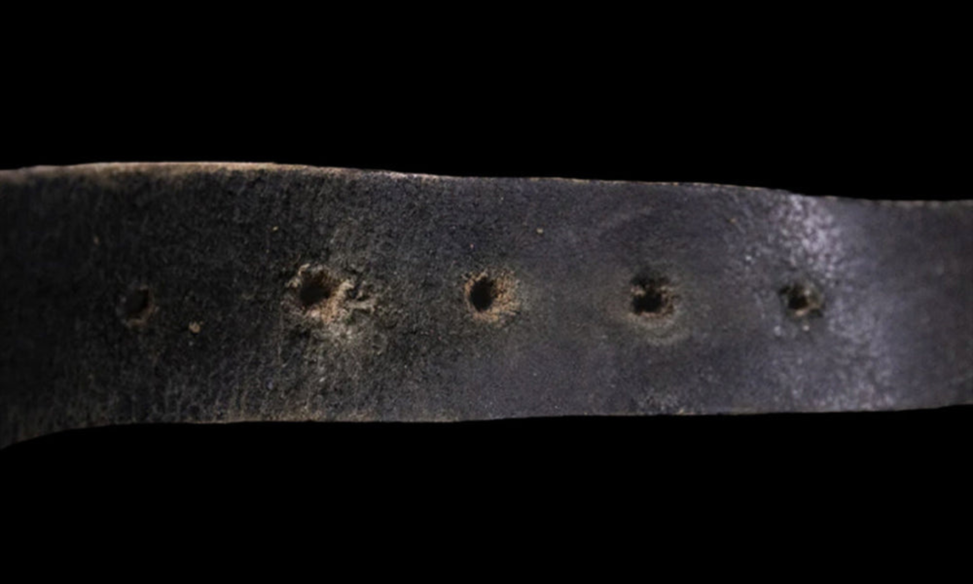 Een versleten en gekreukelde traditionele riem met uitgerekte gaatjes, die de nadelen van ouderwetse riemen laat zien.